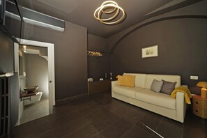 Ein modernes Interieur mit einer Couch, einem Kleiderhaken, einem gerahmten Bild und einer besonderen, runden Leuchte.