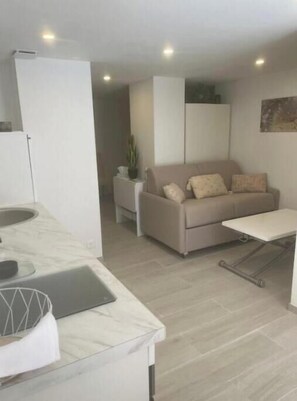 A modern kitchen with a marble countertop, a dining area with a sofa and a small table, and a living space with a couch and a plant. - Lovely Charrons 1 - Large Studio 50 m from the Port, Centre Saint-Tropez (Saint-Tropez)