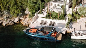 Ein Küstenhaus mit einem Boot, das am Ufer liegt, umgeben von üppiger Vegetation.