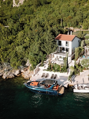 Ein Küstenhaus mit einem Boot, das am Ufer liegt, umgeben von üppiger Vegetation.