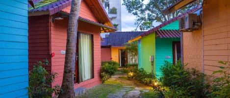 A pathway leading to colorful buildings with a small garden area.