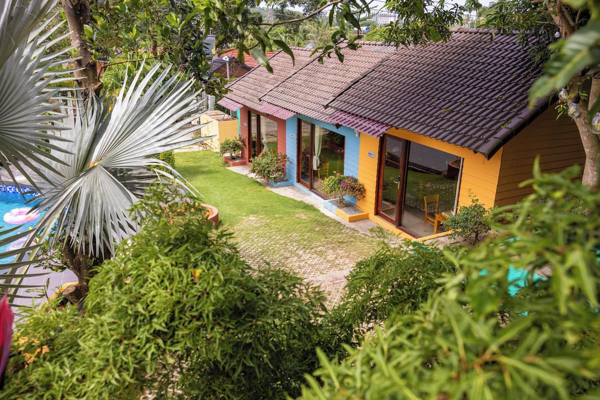 A two-story house with a tiled roof, large windows, and a well-maintained lawn.