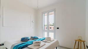 Ein Schlafzimmer mit Bett, Fenster, Nachttisch und Stuhl.