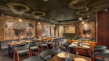 A restaurant with brick walls, large murals, and a mix of seating including tables and booths.