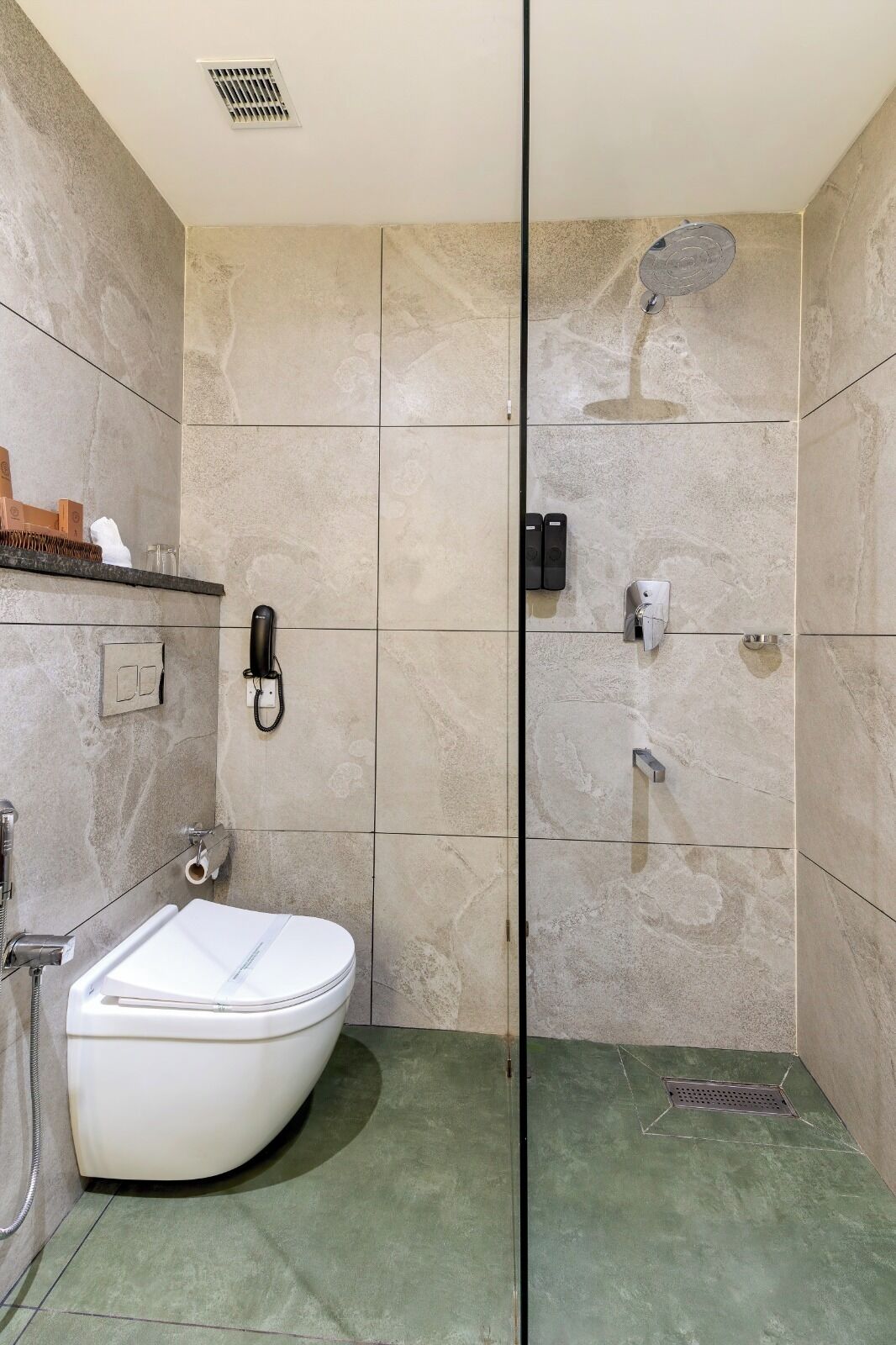 Baño con inodoro, ducha y secador de manos.
