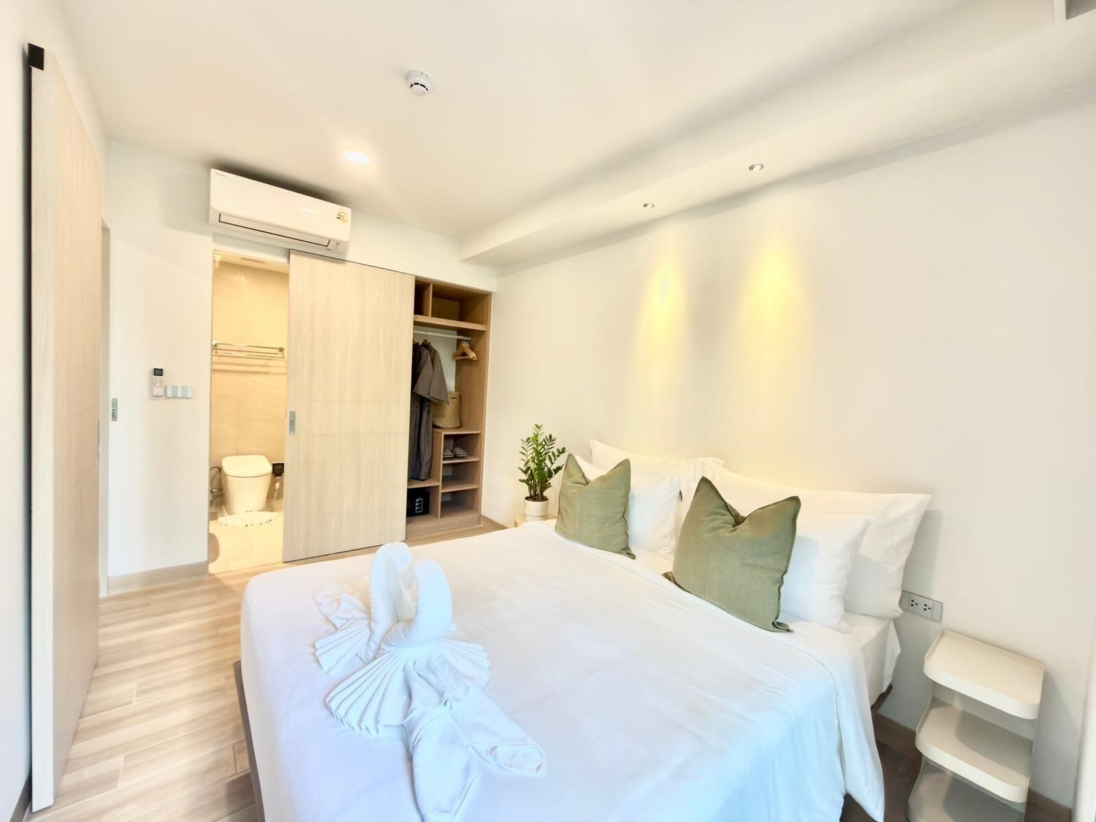 Una habitación de hotel con cama, mesitas de noche, armario y aire acondicionado.