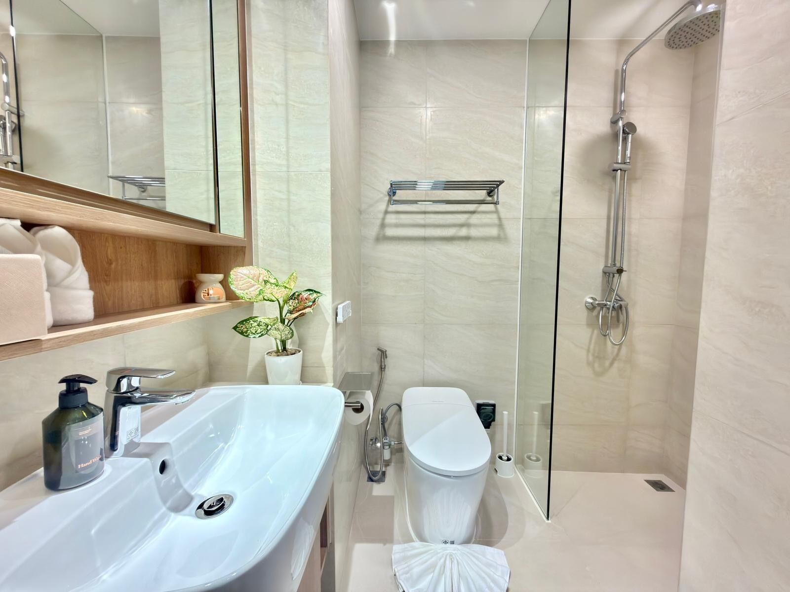 Een moderne badkamer met een douchecabine van glas, een witte wastafel en een toilet.