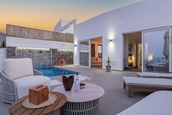 Ein moderner Außenbereich mit Pool, Liegestühlen und einer Steinmauer.