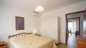 A bedroom with a bed, wardrobe, bedside table, and a painting on the wall. - Casa Elena - Vista Mare & Parcheggio (San Vincenzo)