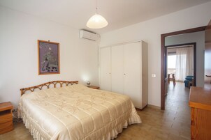 Un dormitorio con cama, armario, mesita de noche y un cuadro en la pared.