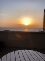 Vista al atardecer desde un balcón con barandilla y pared.
