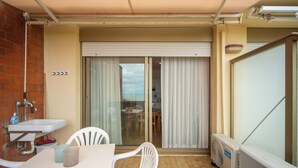 A balcony with a table, chairs, a radiator, and a sliding glass door leading to a room. - Casa Elena - Vista Mare & Parcheggio (San Vincenzo)