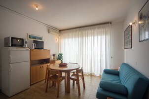 Un espacio habitable compacto con kitchenette, comedor y sofá.