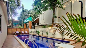 Uma piscina com deck de madeira, espreguiçadeiras e plantas em vasos.