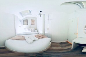 Ein modernes Schlafzimmer mit einem gebogenen Bett, einem Oberlicht, einem Kleiderschrank und einem Nachttisch.