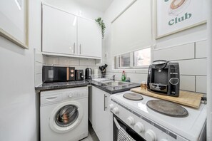 A compact kitchen with a washing machine, microwave, toaster, and coffee maker. - One-Bedroom Deluxe Apartment5 City Cent Manchester (Manchester)