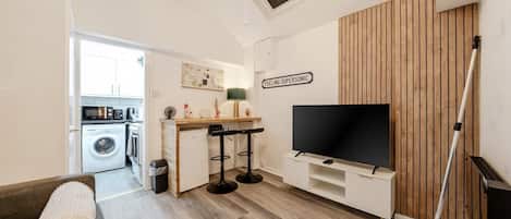 A compact living space with a kitchenette, a TV, and a wooden accent wall.