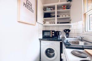 Eine Küche mit Waschmaschine, Mikrowelle, Kaffeemaschine und Spüle.