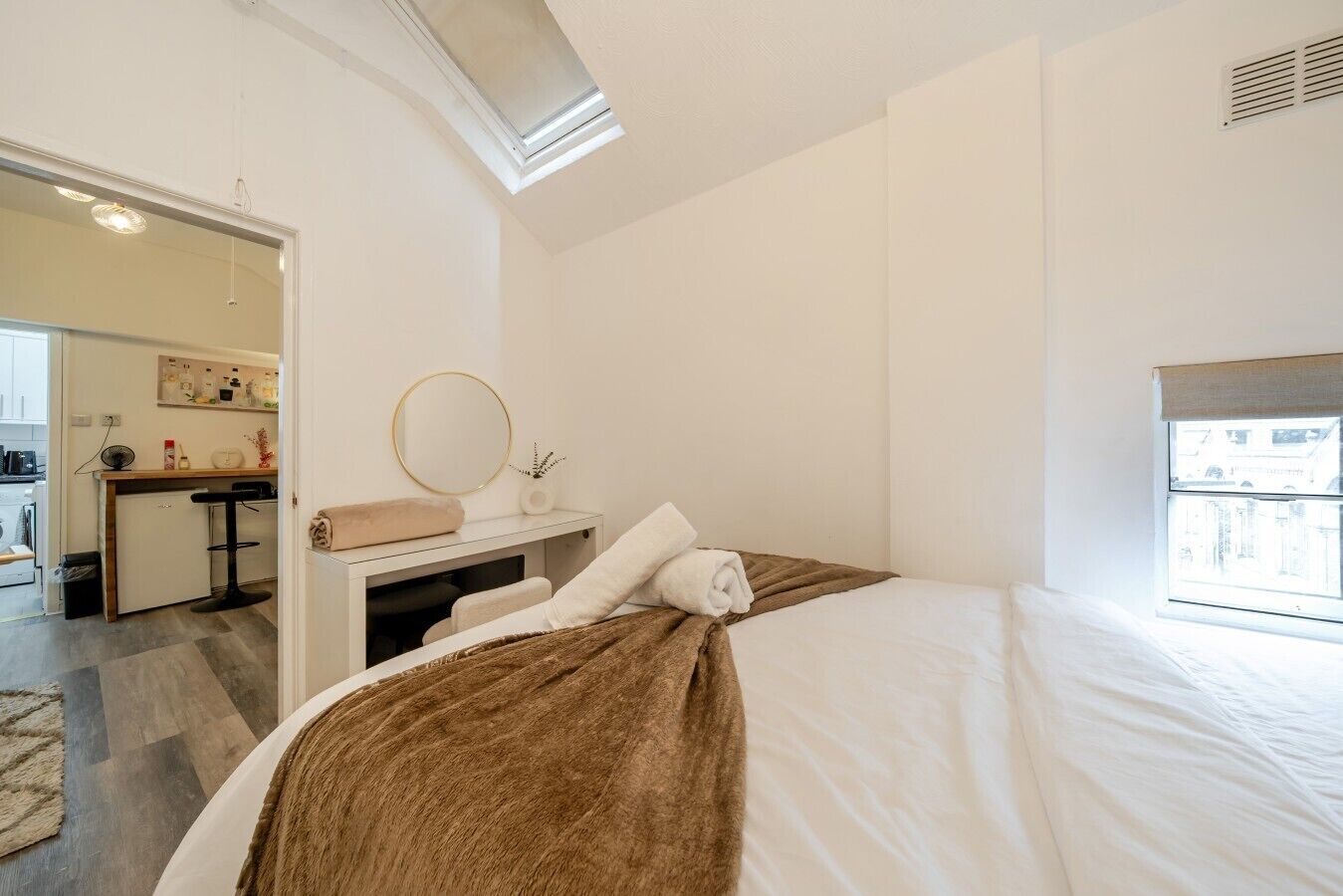 Une chambre à coucher avec un lit, une table de chevet, un miroir et une fenêtre.
