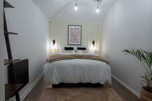 A bedroom with a bed, bedside lamps, a framed picture on the wall, a radiator, and a plant. - One-Bedroom Deluxe Apartment6 City Cent Manchester (Manchester)