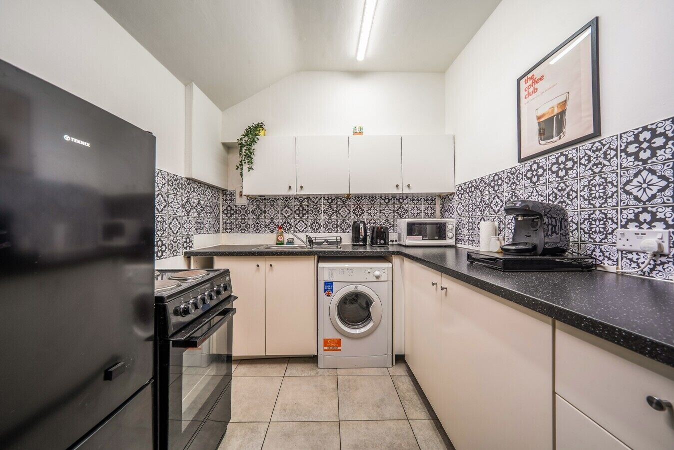 A compact kitchen with a stove, microwave, and washing machine.