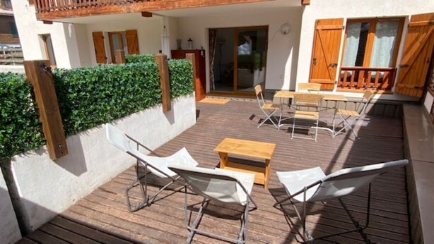 An outdoor deck with a wooden table and chairs, a small wooden bench, and a view of the building's interior. - VALBERG TOWN CENTRE - 3 rooms (50m2) 2 bedrooms + 36m2 terrace (VALBERG)