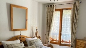 A bedroom with a bed, a mirror, a window with curtains, and a ceiling light. - VALBERG TOWN CENTRE - 3 rooms (50m2) 2 bedrooms + 36m2 terrace (VALBERG)