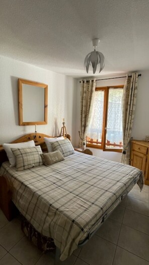 A bedroom with a bed, a mirror, a window with curtains, and a ceiling light. - VALBERG TOWN CENTRE - 3 rooms (50m2) 2 bedrooms + 36m2 terrace (VALBERG)