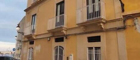 Un edificio amarillo con balcones, plantas en macetas y un farol.