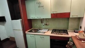 Cocina compacta con estufa, pileta y un armario identificado con la etiqueta 'Coffee Always'.