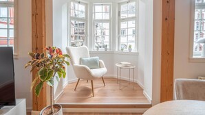 A cozy room with a white chair, a small table, and a potted plant. - Stylish vacation apartment at Kornmarkt | Limburg (Limburg)