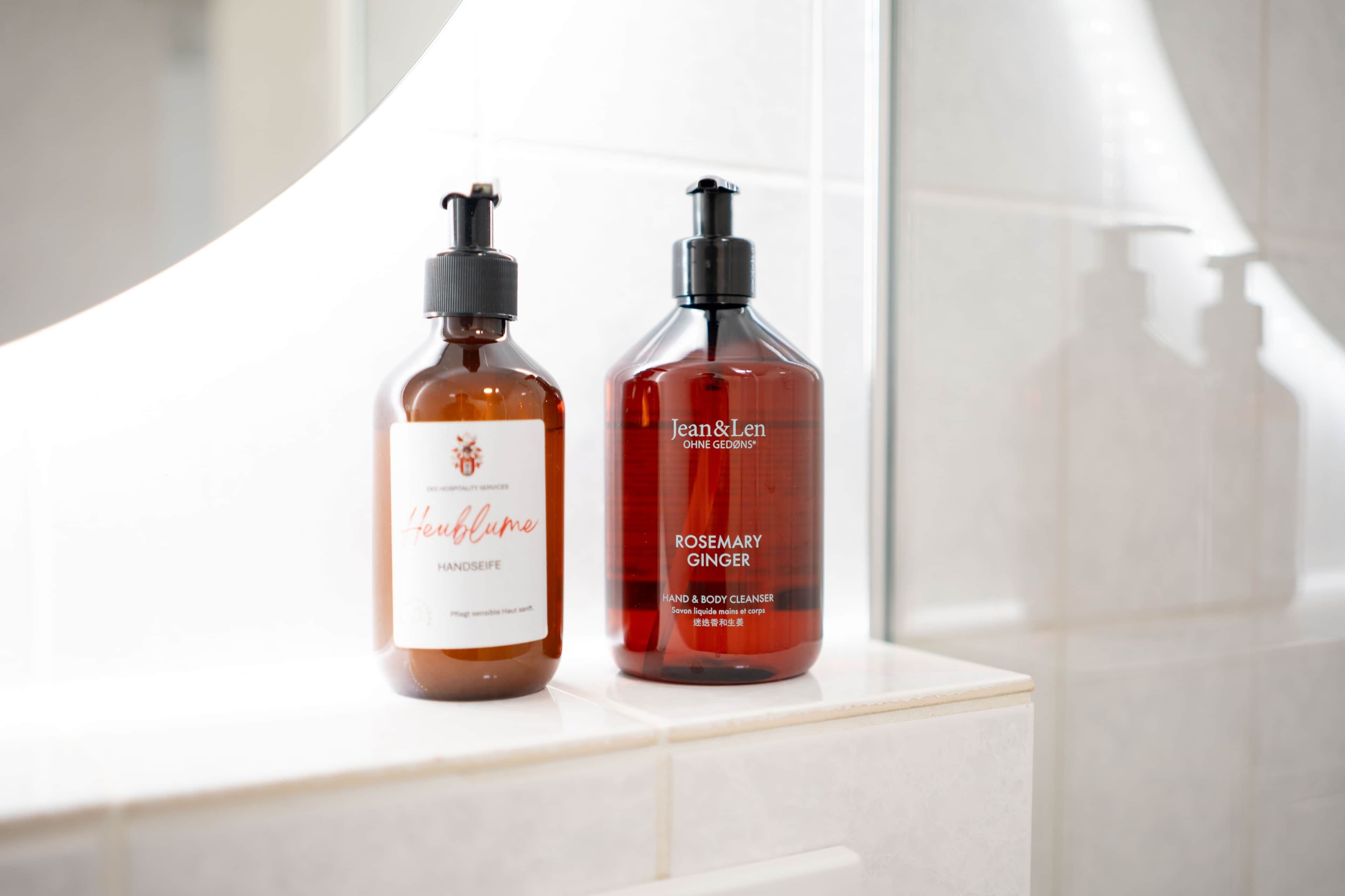 Deux flacons de produit nettoyant pour les mains et le corps, posés sur une surface blanche.