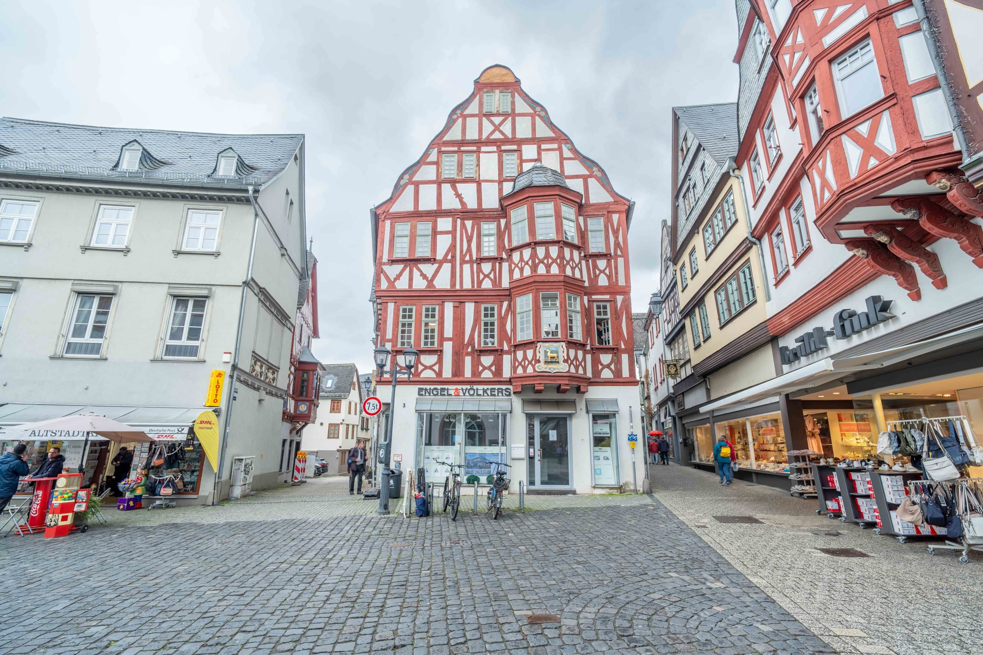 A cobblestone street with traditional half-timbered buildings, a bicycle, and a storefront named 'ENGEL VÖLKERS.'