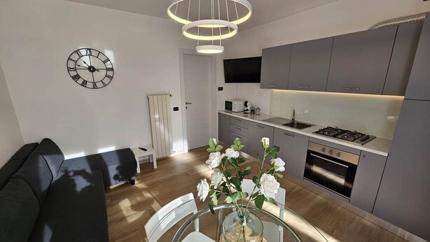 A modern kitchen with a built-in oven and a dining area with a glass table and chairs. - GREY1 (air conditioning and free private parking) (Verbania)