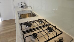 A modern kitchen with a gas stove, stainless steel sink, and white cabinetry. - GREY1 (air conditioning and free private parking) (Verbania)