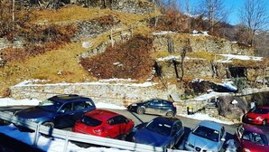 Ein Parkplatz mit Autos und einer Steinsäule im Hintergrund.