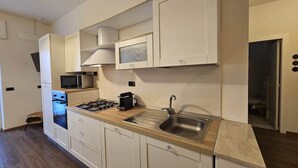 Eine kompakte Küche mit weißen Schränken, einer Mikrowelle, einem Backofen, einem Spülbecken und einer Arbeitsplatte.