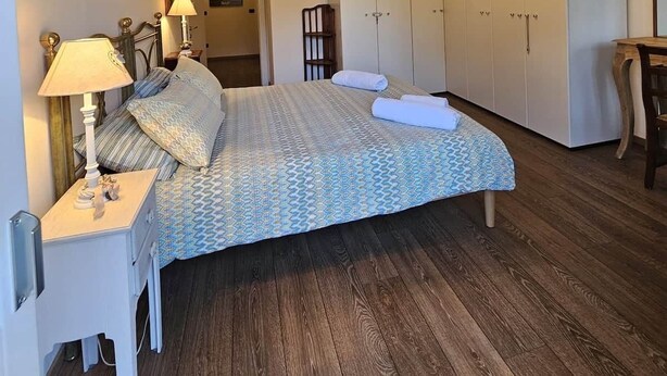 Ein Schlafzimmer mit Bett, Nachttischlampen, einem Kleiderschrank und einem Schreibtisch.
