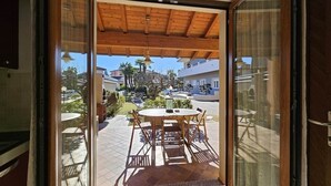 Una habitación con puerta de vidrio corrediza que da a un patio exterior con mesa y sillas.