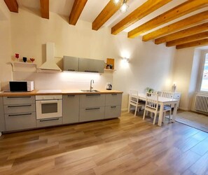 A modern kitchen with wooden beams, a dining area, and a window. - MATILDE APARTMENT LAKE CENTER (Verbania)