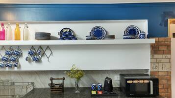 Una cocina con microondas, cafetera y diferentes utensilios de cocina en estantes.