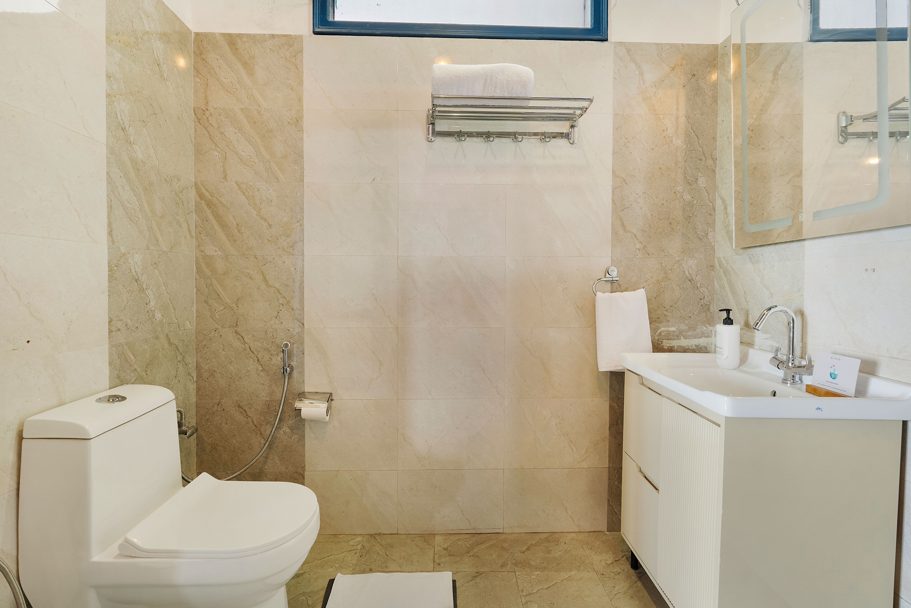 A bathroom with a toilet, shower, sink, and towel rack.