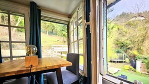 Una habitación con una mesa de madera, dos sillas y vistas a un jardín a través de amplios ventanales.