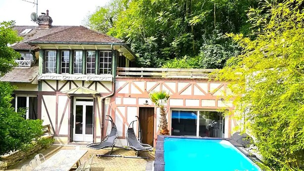 Una casa con piscina, un patio con sillas y un jardín.