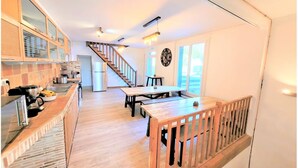 Una cocina con mostrador de madera, un refrigerador y una zona de comedor con mesa y sillas.