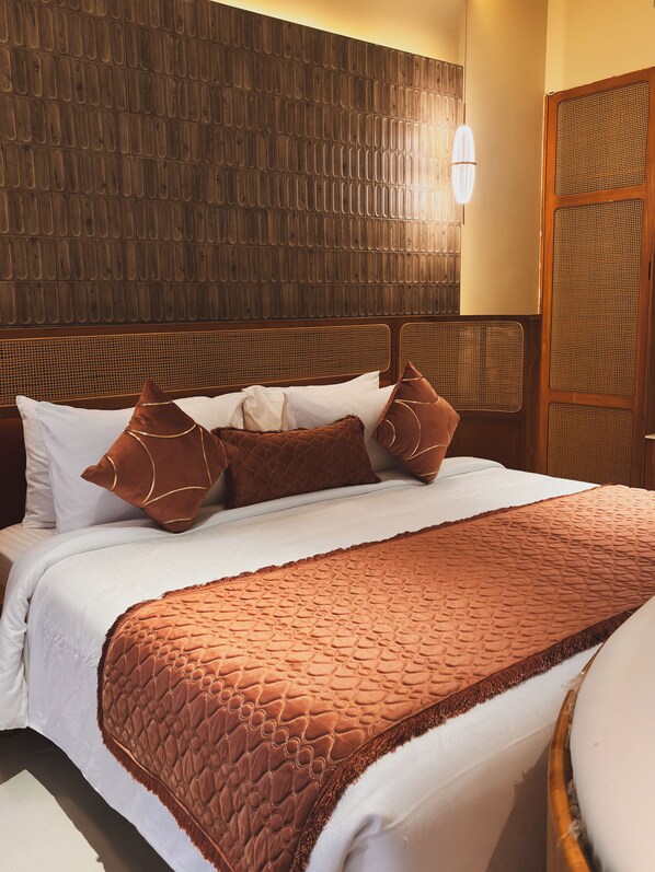 A hotel room with a bed, a headboard with a woven pattern, and a wall with a textured design. - AVANYA RESORTS & RETREAT (Kilpennathur)