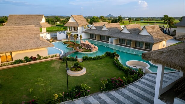 A resort with thatched-roof buildings, a central swimming pool, and a well-maintained lawn. - AVANYA RESORTS & RETREAT (Kilpennathur)