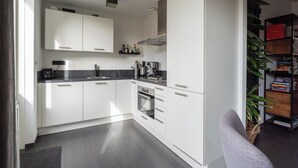 Une cuisine moderne avec des armoires blanches, un plan de travail noir et un four encastré.