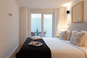 Ein Hotelzimmer mit Bett, einem Frühstücksbrett, einem Balkon mit Tisch und Stühlen sowie einem Bild an der Wand.