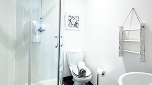 Une salle de bain avec une douche à parois de verre, des toilettes blanches, un lavabo blanc et un porte-serviettes.